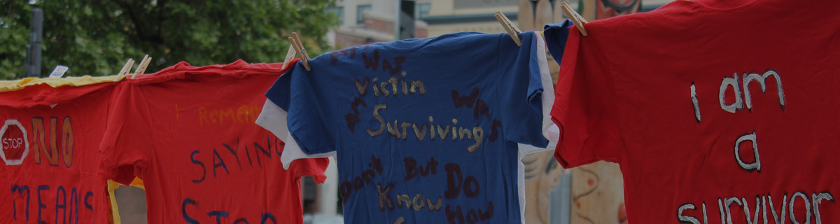 t-shirts hang on a line with text written on them saying various things that survivors wanted to write about: 
