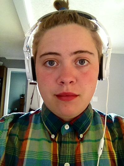 Eunice with headphones and green plaid shirt at work