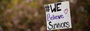 A sign that says "#We Believe Survivors"